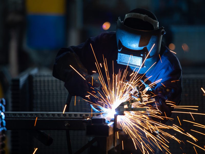 Workers wearing industrial uniforms and Welded Iron Mask at Steel welding plants, industrial safety first concept.